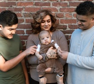 A Woman Carrying Her Baby Boy while Standing Between the Father and His Son